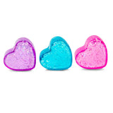 Three translucent heart-shaped soaps in purple, blue, and pink with glitter accents are arranged in a row on a white background.