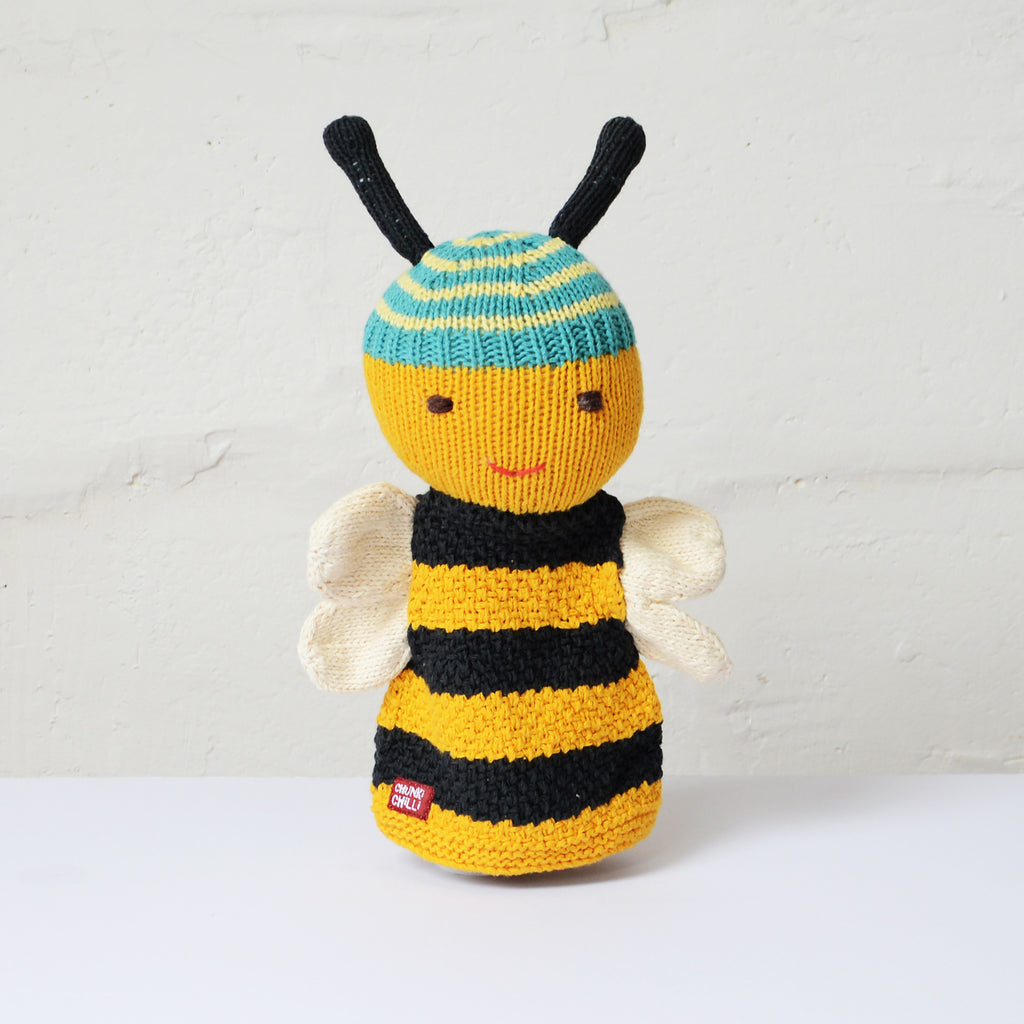 A cheerful knitted hand puppet by ChunkiChilli featuring a bee with black and yellow stripes, white wings, a blue and yellow striped head, and black antennae, displayed against a white background.
