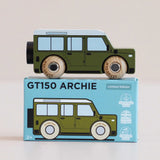 Side view of a green wooden toy car resting on top of its matching blue packaging box.