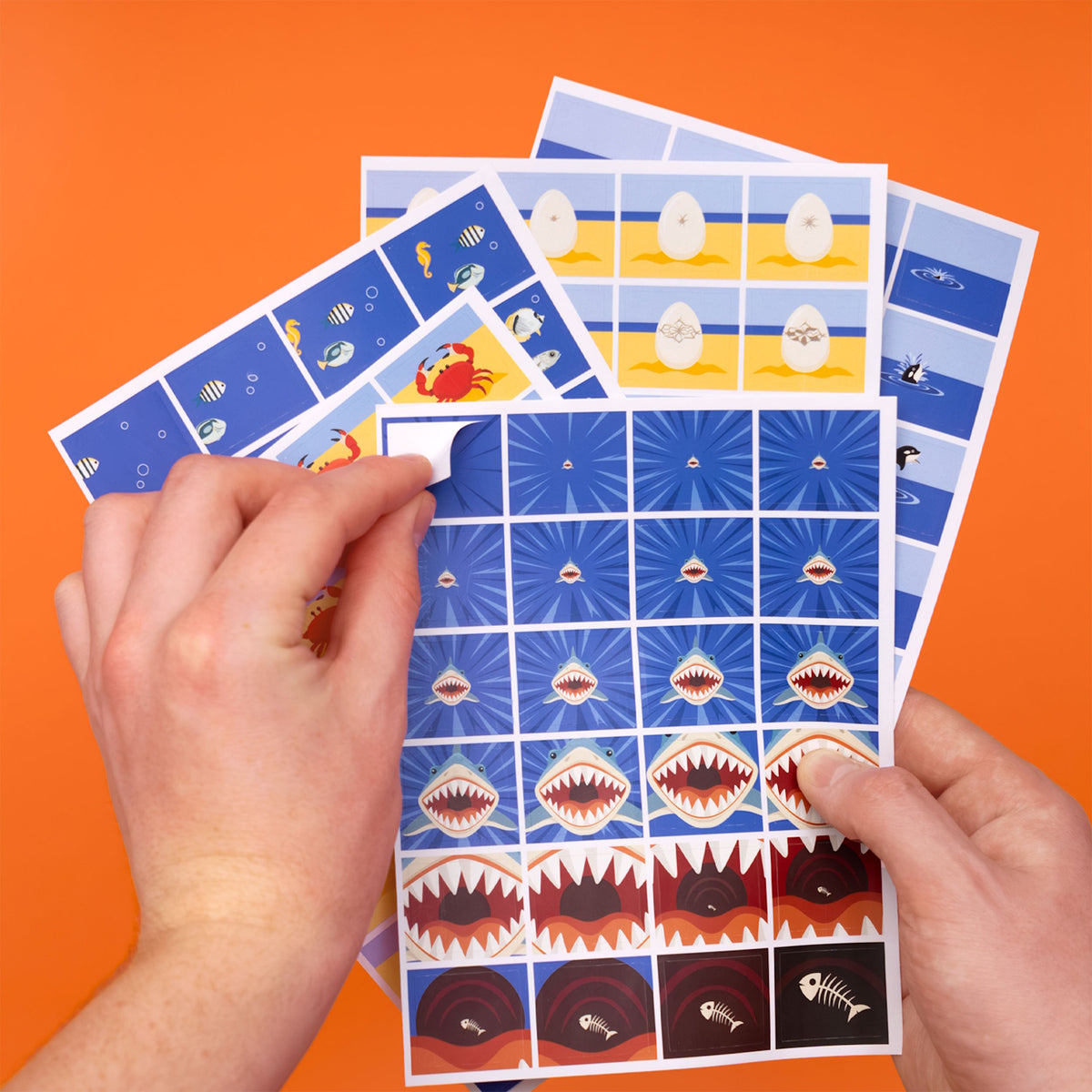 Hands peeling a sticker from a sheet of ocean-themed animation stickers on an orange background.