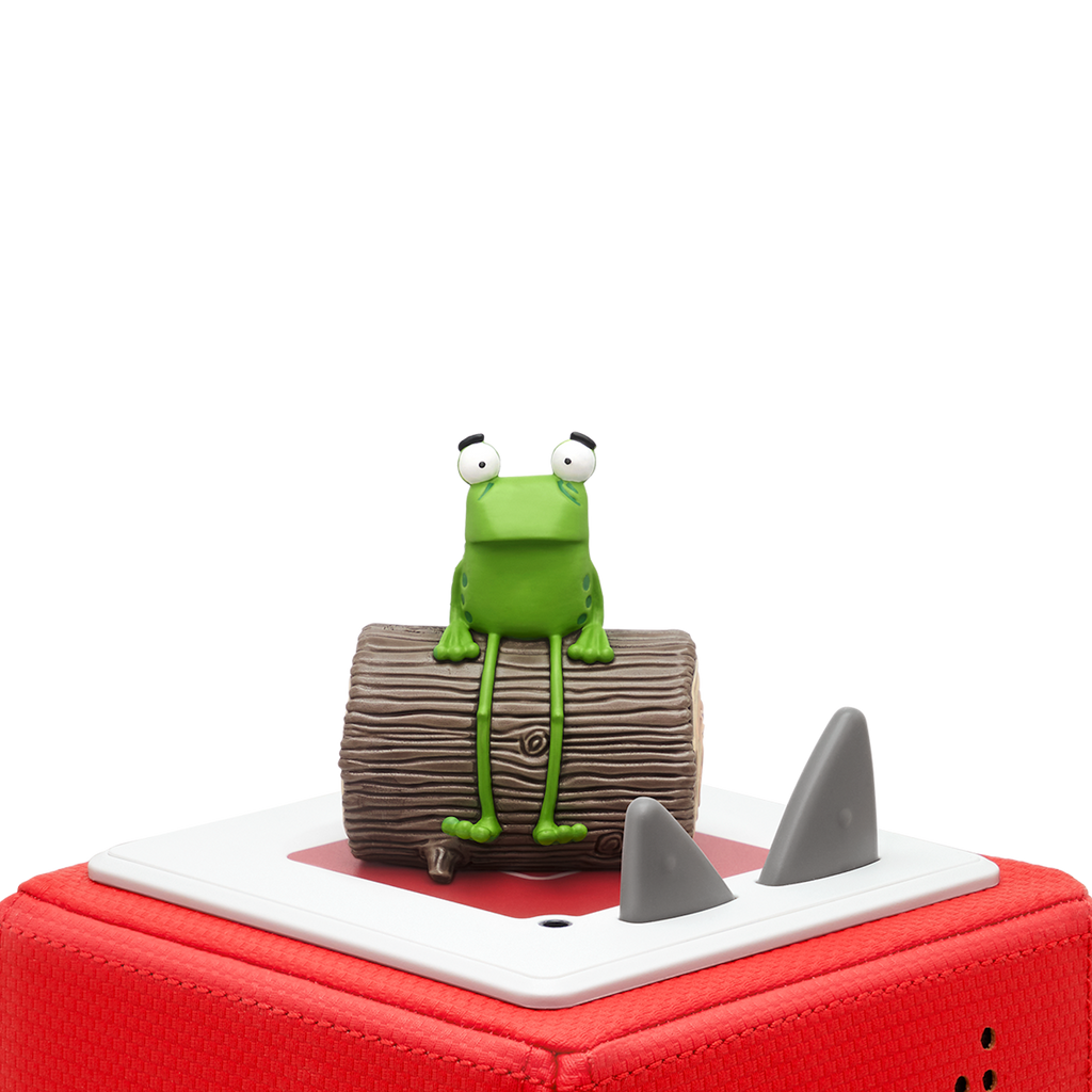 A playful green frog figurine with large eyes, sitting on a textured brown log against a white background.
