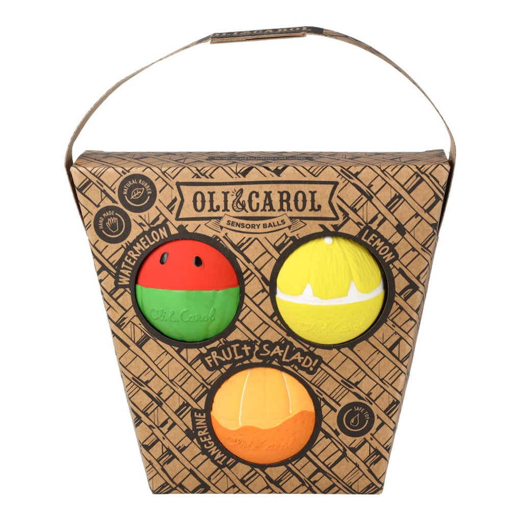 Packaging of sensory balls shaped like watermelon, lemon, and tangerine by Oli & Carol. The box is basket-patterned with a handle. Fun and playful design.