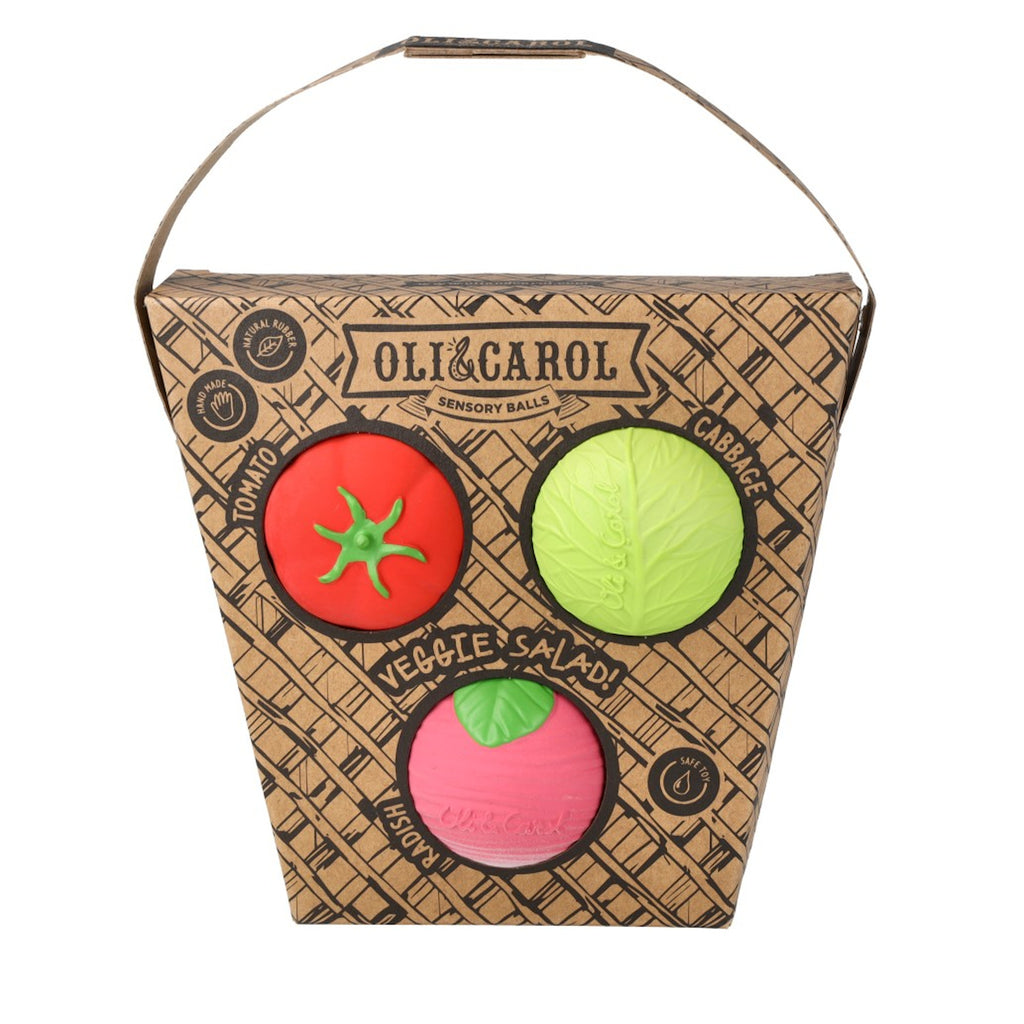 Cardboard box with three sensory balls resembling a tomato, cabbage, and radish. The box reads "Oli&Carol Veggie Salad" and features eco-friendly icons.
