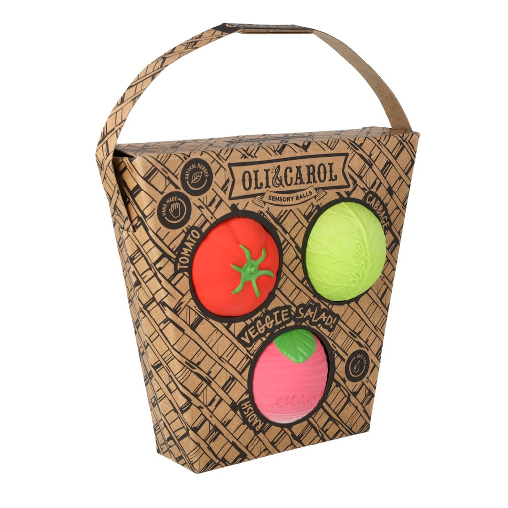 Cardboard box with three sensory balls resembling a tomato, cabbage, and radish. The box reads "Oli&Carol Veggie Salad" and features eco-friendly icons.
