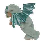 Plush baby doll in a green dragon onesie with sparkly wings and horns. The doll's eyes are closed, and it conveys a peaceful, sleepy expression.