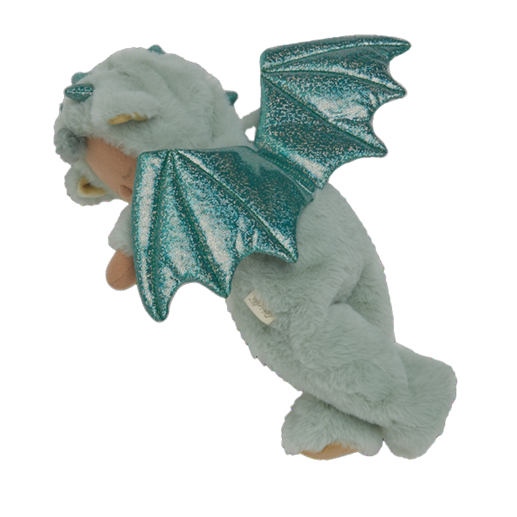 Plush baby doll in a green dragon onesie with sparkly wings and horns. The doll's eyes are closed, and it conveys a peaceful, sleepy expression.