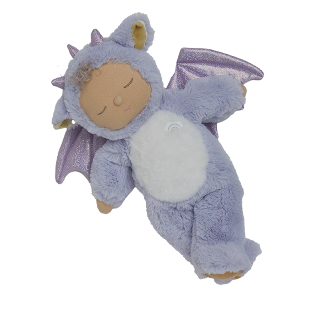 Cute plush doll in a purple dragon costume with sparkly wings. The doll has a serene expression, curly hair, and a small rainbow emblem.