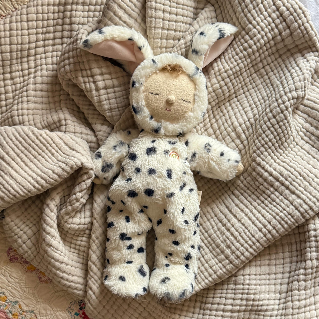 Cute plush doll wearing a soft, white Dalmatian costume with black spots and floppy ears. The doll has closed eyes.