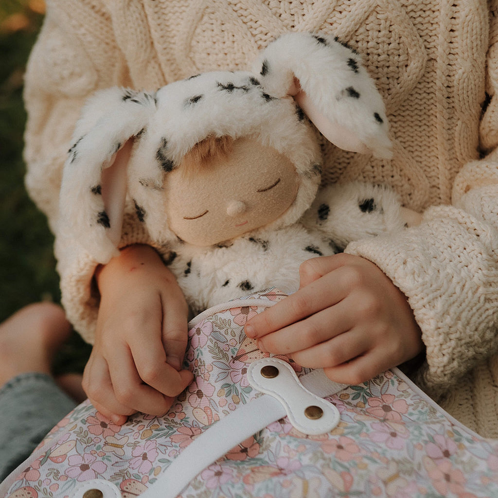 Cute plush doll wearing a soft, white Dalmatian costume with black spots and floppy ears. The doll has closed eyes.