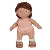 A soft, fabric doll with brown pigtails stands against a white background. It wears a pink romper and brown shoes, conveying a playful and charming tone.
