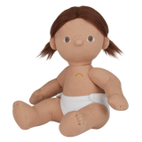 A soft, fabric doll with brown pigtails stands against a white background. It wears a pink romper and brown shoes, conveying a playful and charming tone.