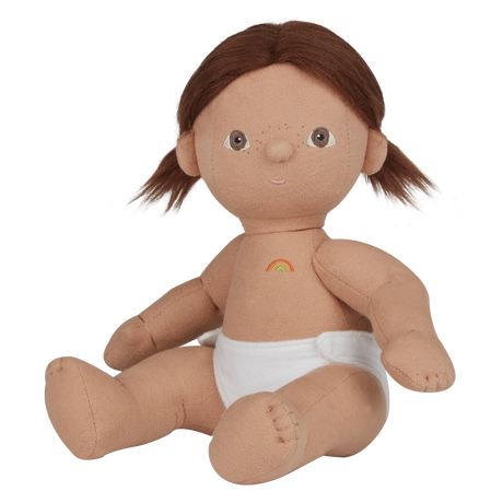 A soft, fabric doll with brown pigtails stands against a white background. It wears a pink romper and brown shoes, conveying a playful and charming tone.