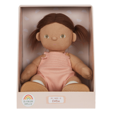 A soft, fabric doll with brown pigtails stands against a white background. It wears a pink romper and brown shoes, conveying a playful and charming tone.