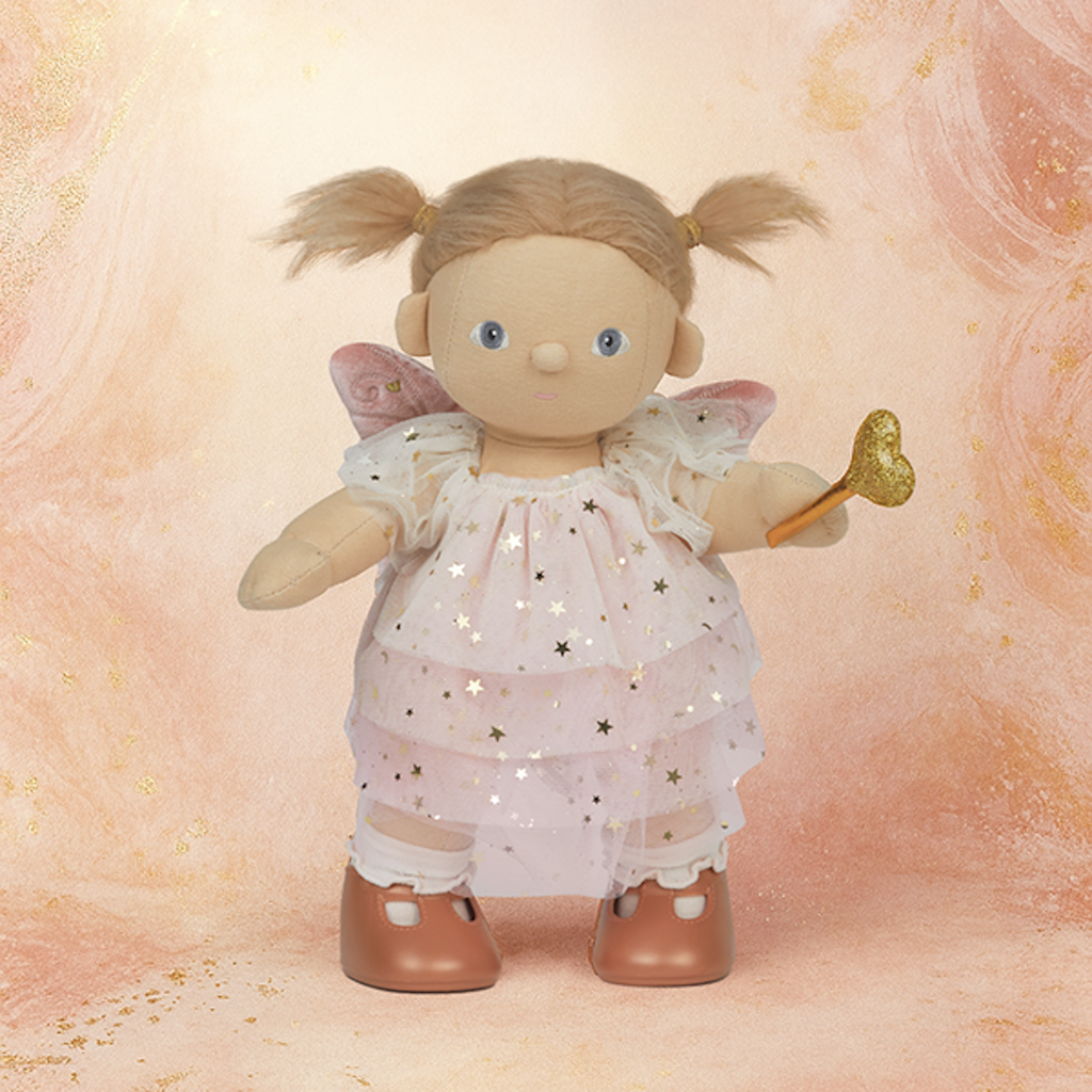A cute fabric doll with blonde pigtails, wearing a starry pink dress and holding a golden heart-shaped wand. The background is a warm peach texture.