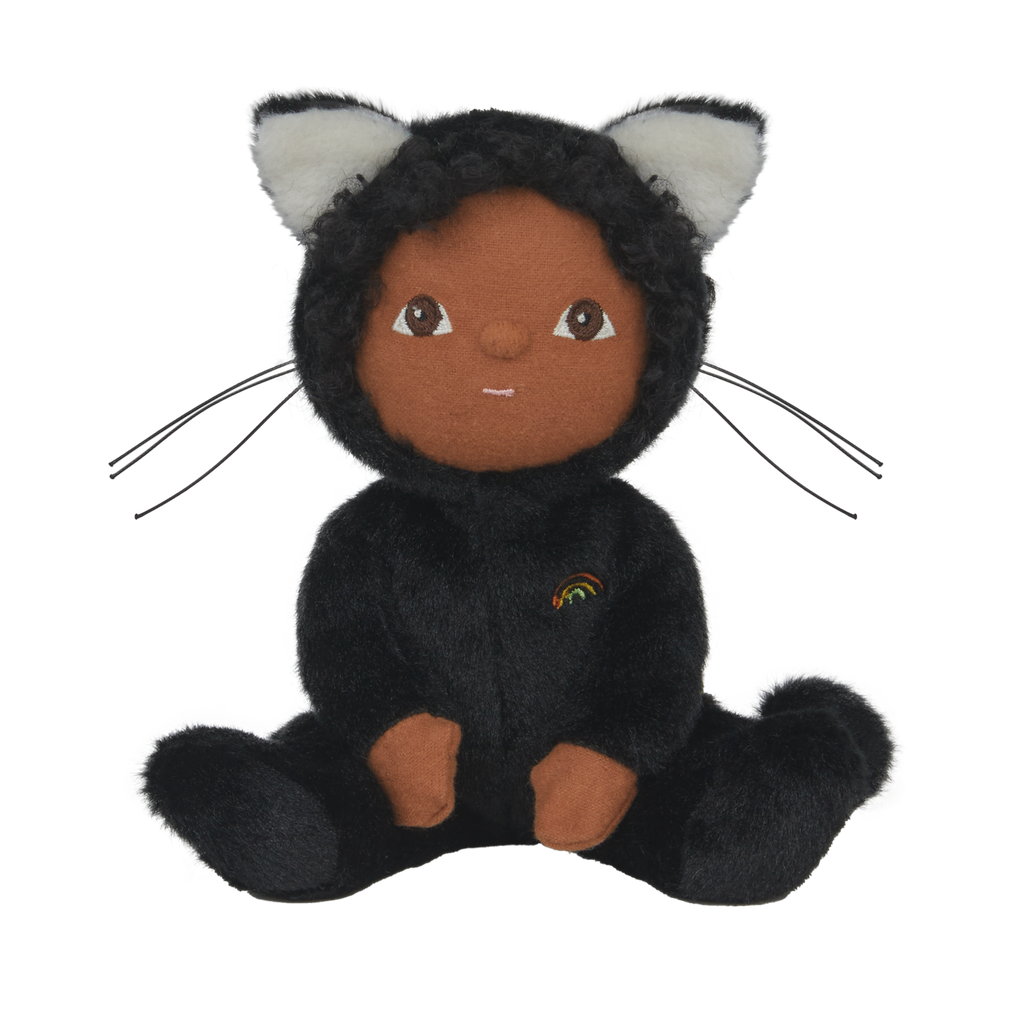 Cuddly doll in a black cat outfit with white ears and embroidered rainbow. It has a gentle expression, sitting against a white background.
