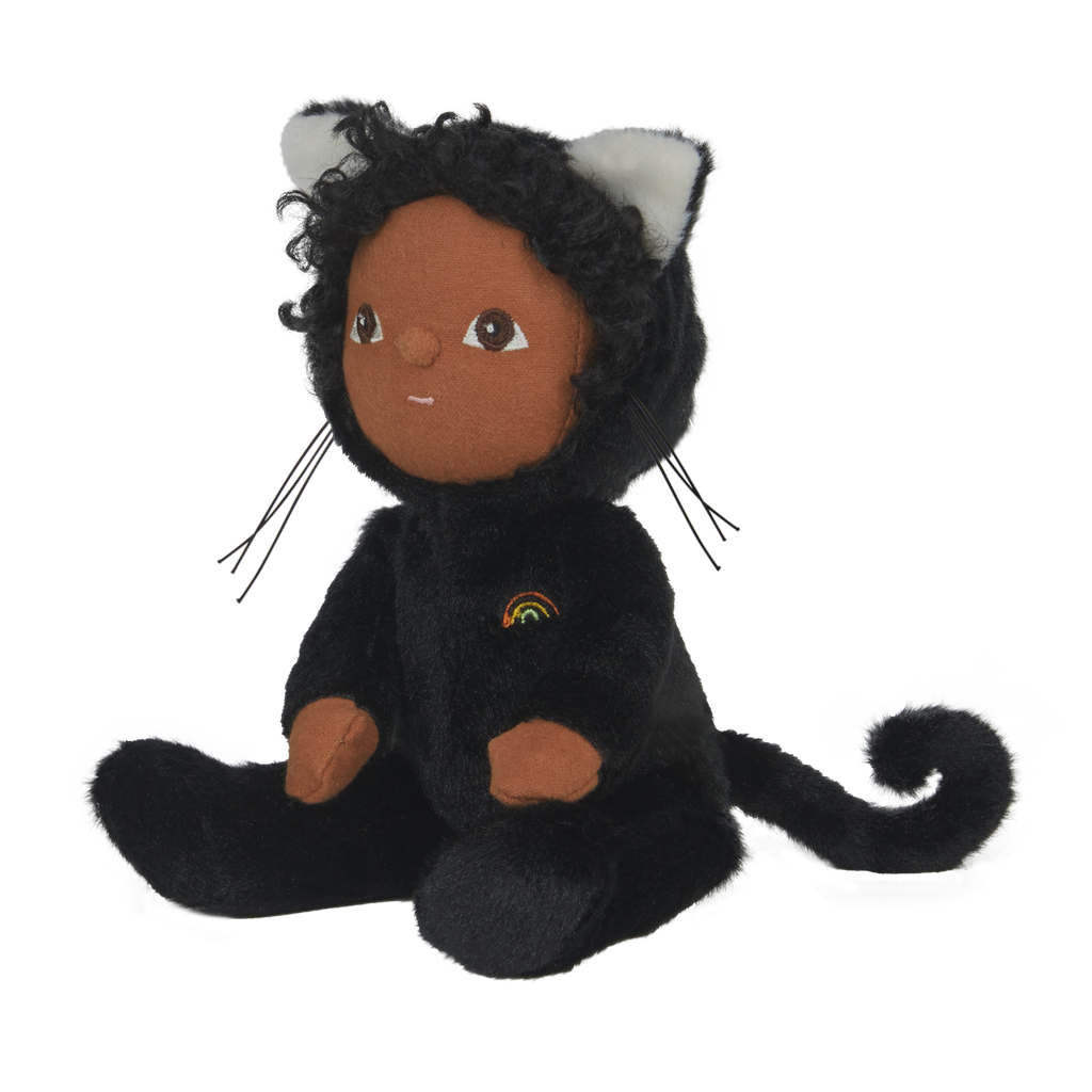 Cuddly doll in a black cat outfit with white ears and embroidered rainbow. It has a gentle expression, sitting against a white background.