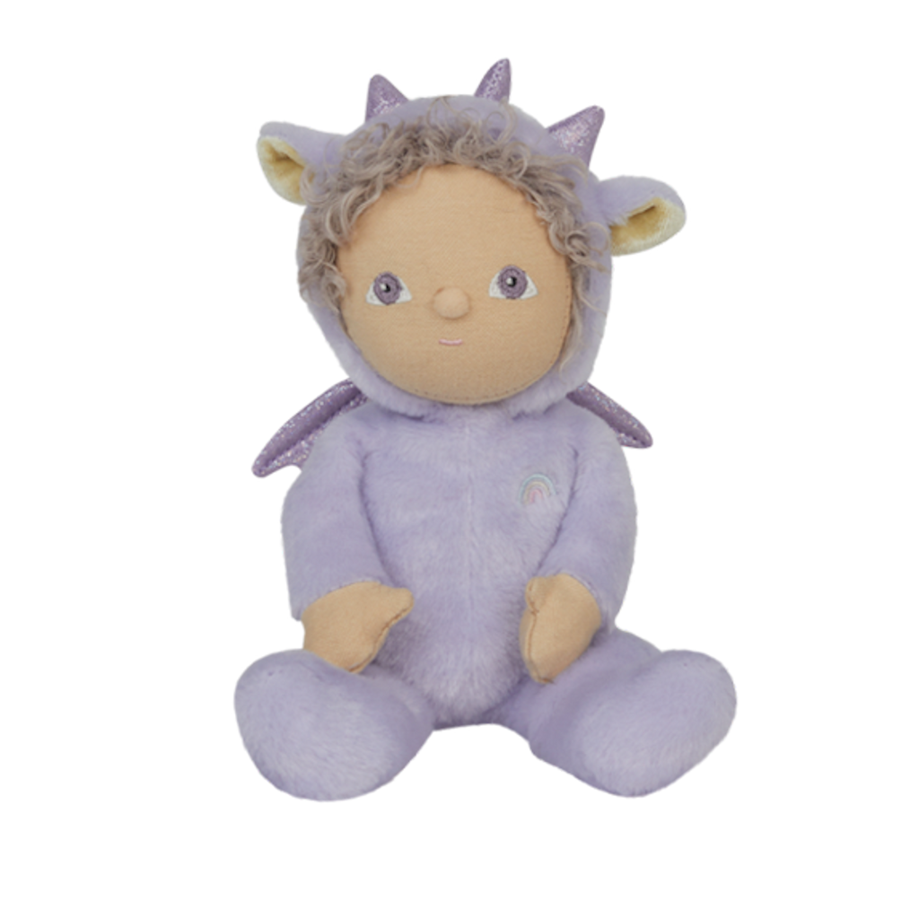 A plush doll wearing a lavender dragon costume with sparkly ears and horns. The doll has curly hair, a serene expression, and a rainbow emblem.