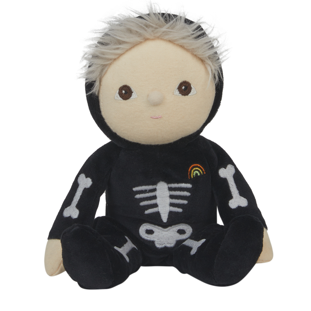 Cute plush doll with light hair in a black skeleton costume, featuring bone designs and a small rainbow patch. The doll has a neutral expression.