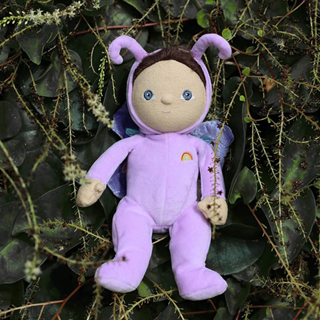 A soft doll in a purple butterfly costume with antennae and wings, featuring a small rainbow emblem. The doll has a gentle, welcoming expression.