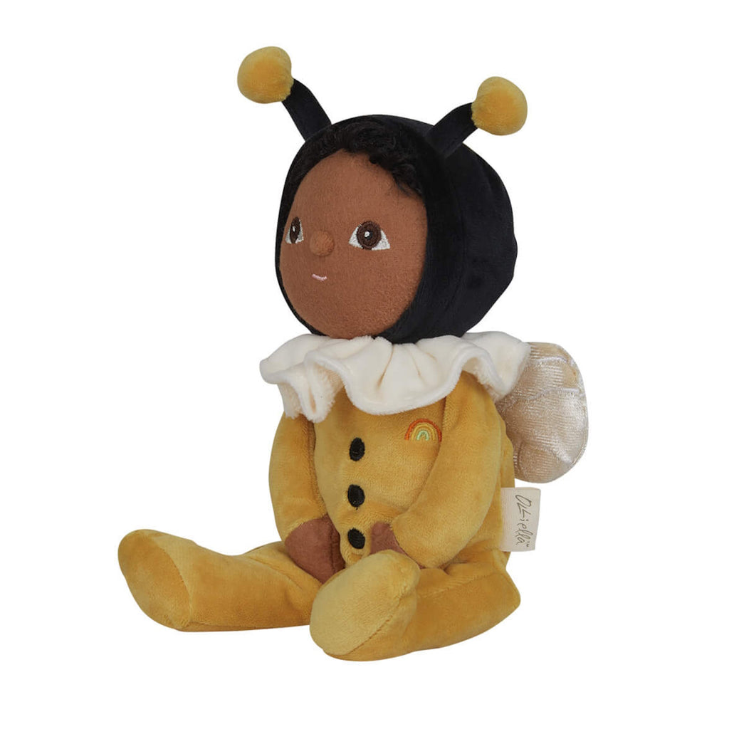 Plush doll dressed as a bee, featuring a black head with bee antennae, a white ruffled collar, and yellow outfit with wing details, sitting upright.