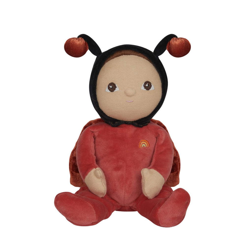 Soft plush toy resembling a ladybug figure, wearing a red outfit with a rainbow patch. Features a gentle facial expression and antennae on its hood.
