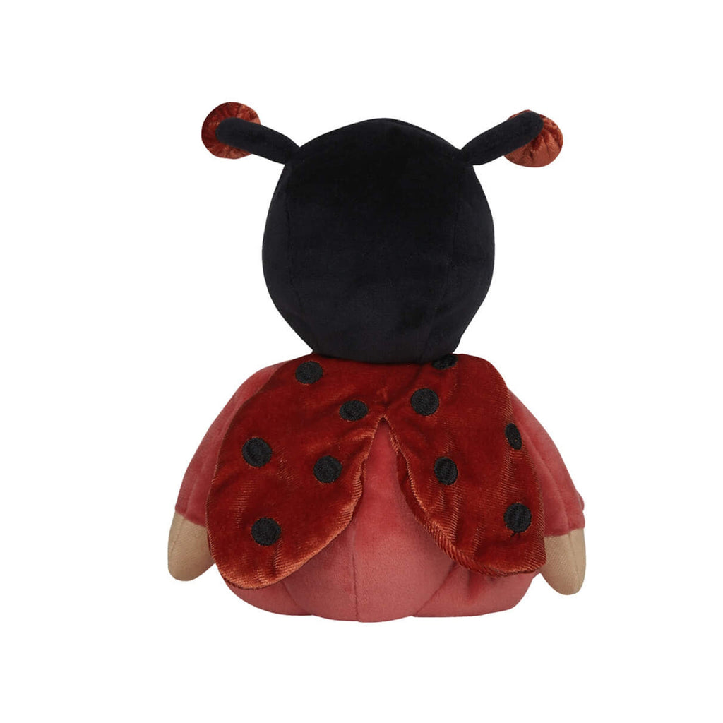 Soft plush toy resembling a ladybug figure, wearing a red outfit with a rainbow patch. Features a gentle facial expression and antennae on its hood.