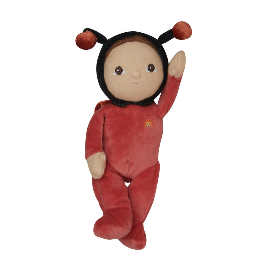 Soft plush toy resembling a ladybug figure, wearing a red outfit with a rainbow patch. Features a gentle facial expression and antennae on its hood.