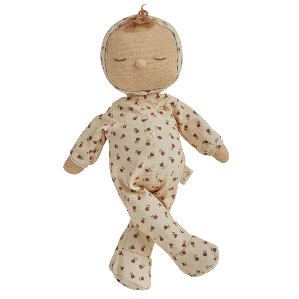 A soft doll in a cream-colored outfit with red strawberry patterns. The doll has closed eyes, curly hair on top, and small mittens and booties.