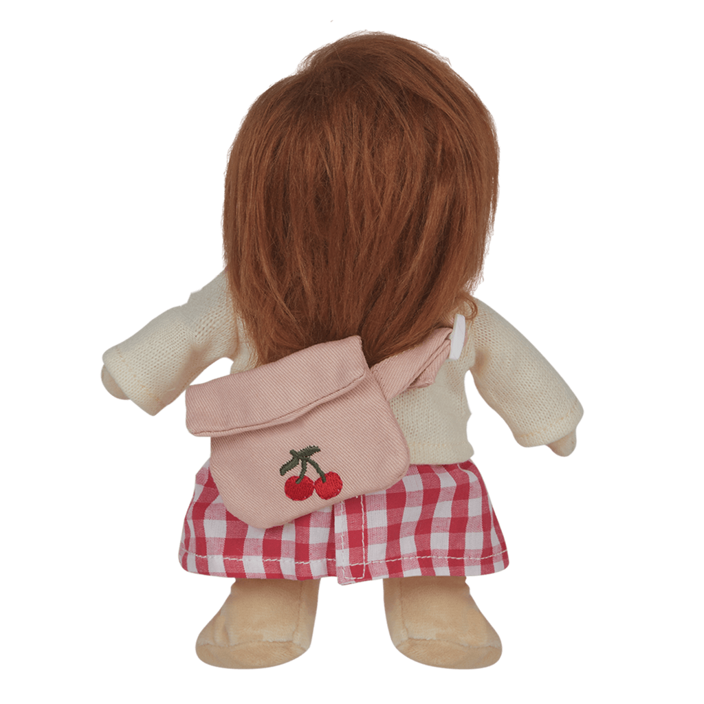 A soft, brown-haired doll wearing a cream sweater with a cherry design, pink checked skirt, and matching cherry bag, set against a white background.