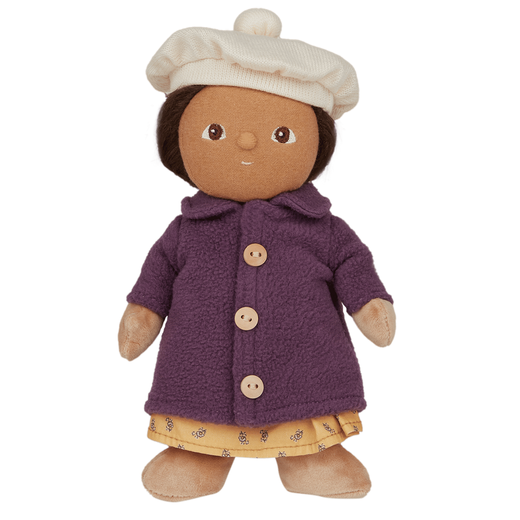 Plush doll with a soft brown face, wearing a cream beret, purple buttoned coat, and yellow dress with patterns, against a white background.
