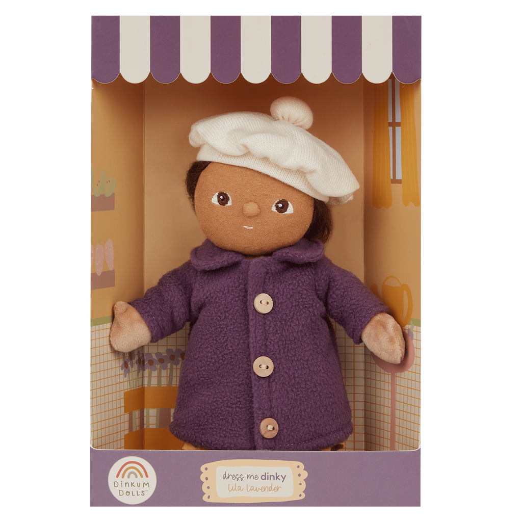 A plush doll with brown hair, wearing a purple coat and white chef's hat, is displayed in a decorative box with purple and white striped edges.