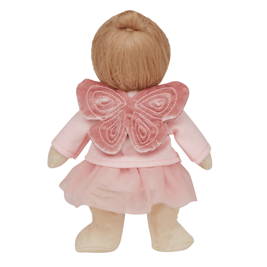 A doll wearing a pink dress with tulle and butterfly wings stands with its back facing. The doll has light brown hair and soft beige limbs, set against a white background.
