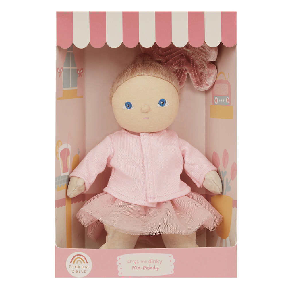 Soft doll in pink tutu and jacket, packaged in a pink box with a striped canopy design. The doll has blue eyes, a gentle smile, and a bow on her head.