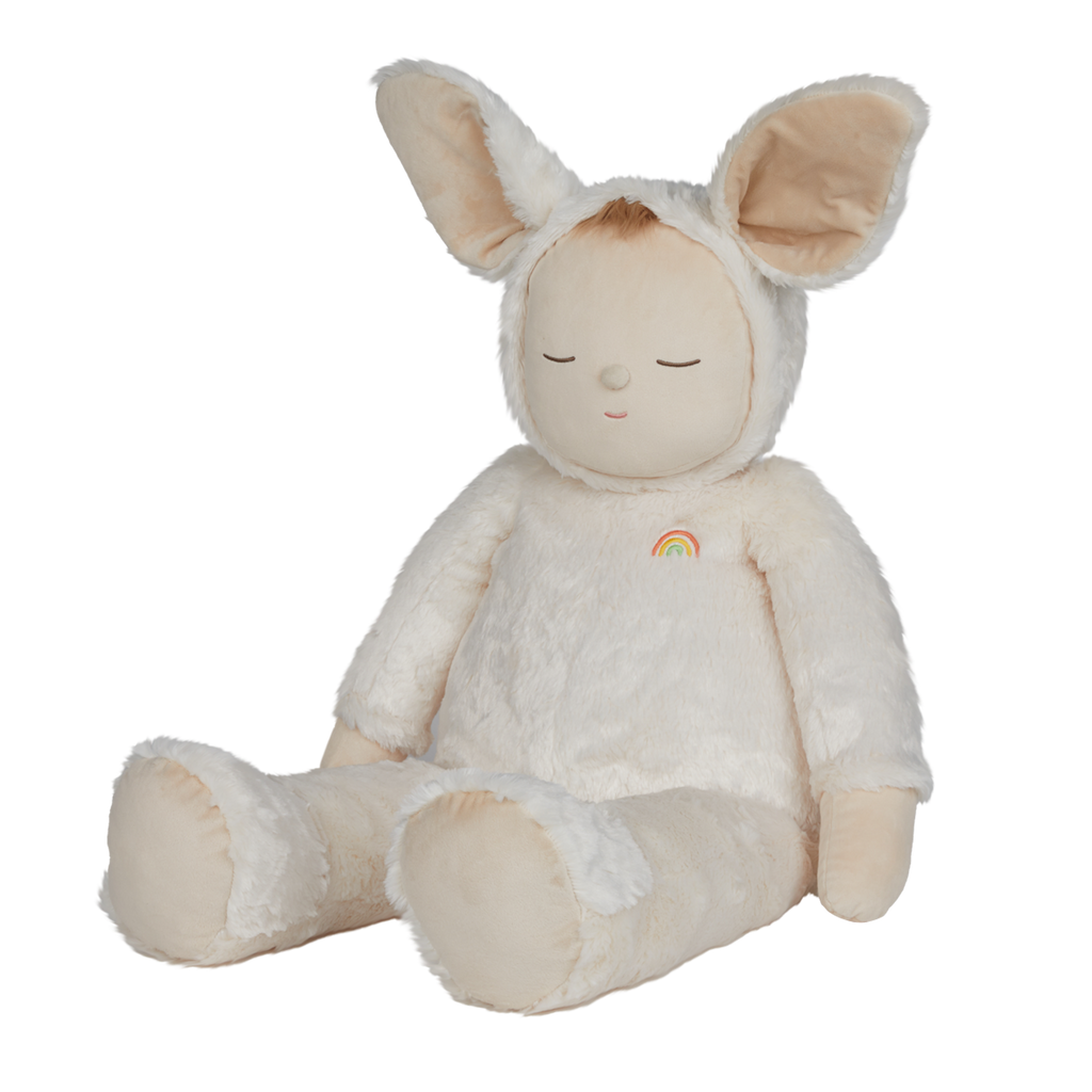 A plush toy with closed eyes, wearing a soft, white bunny suit with large ears. It has a small rainbow patch on its chest, conveying calmness.