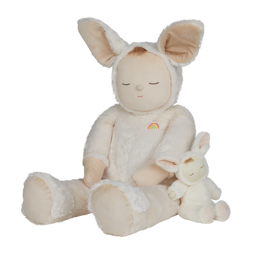 A plush toy with closed eyes, wearing a soft, white bunny suit with large ears. It has a small rainbow patch on its chest, conveying calmness.