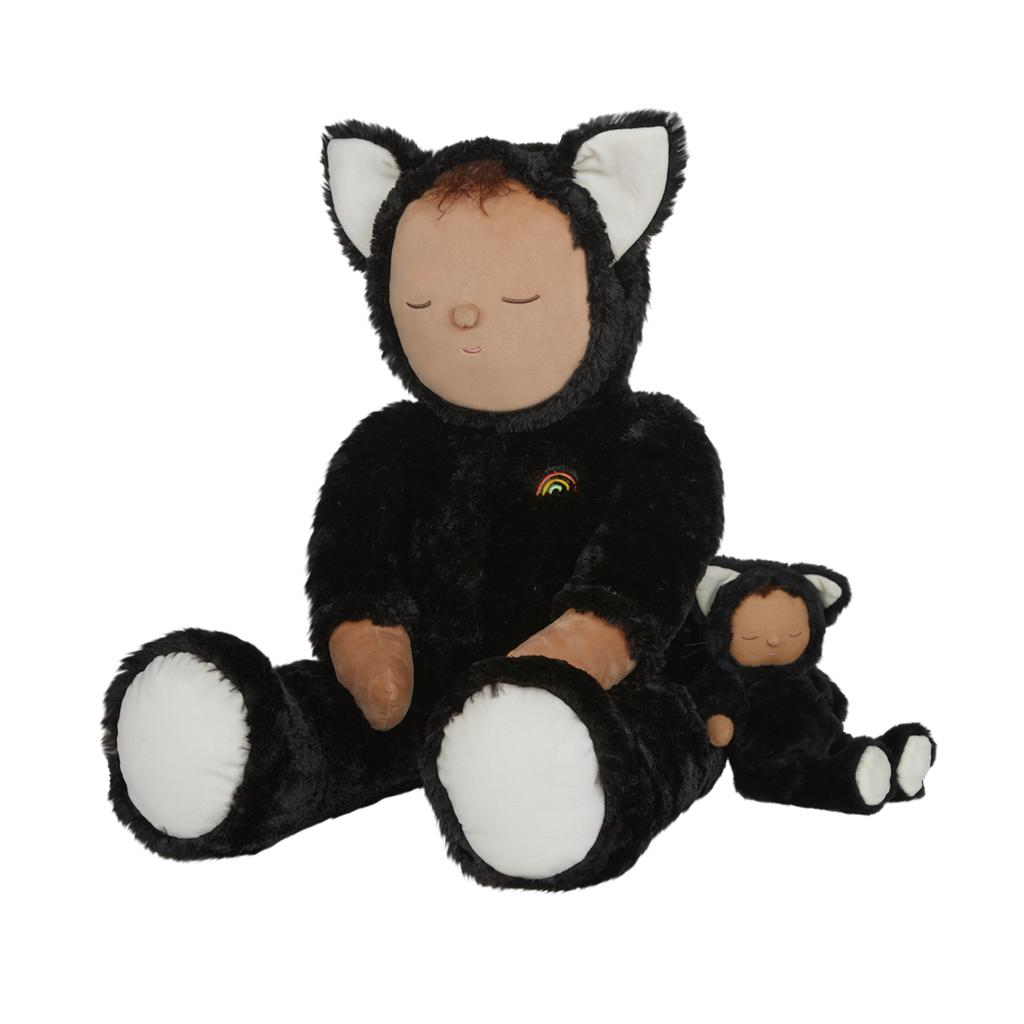 Plush doll dressed as a cat with black fur, white paws and ears, and a tiny rainbow on its chest. The doll's eyes are closed, creating a peaceful expression.