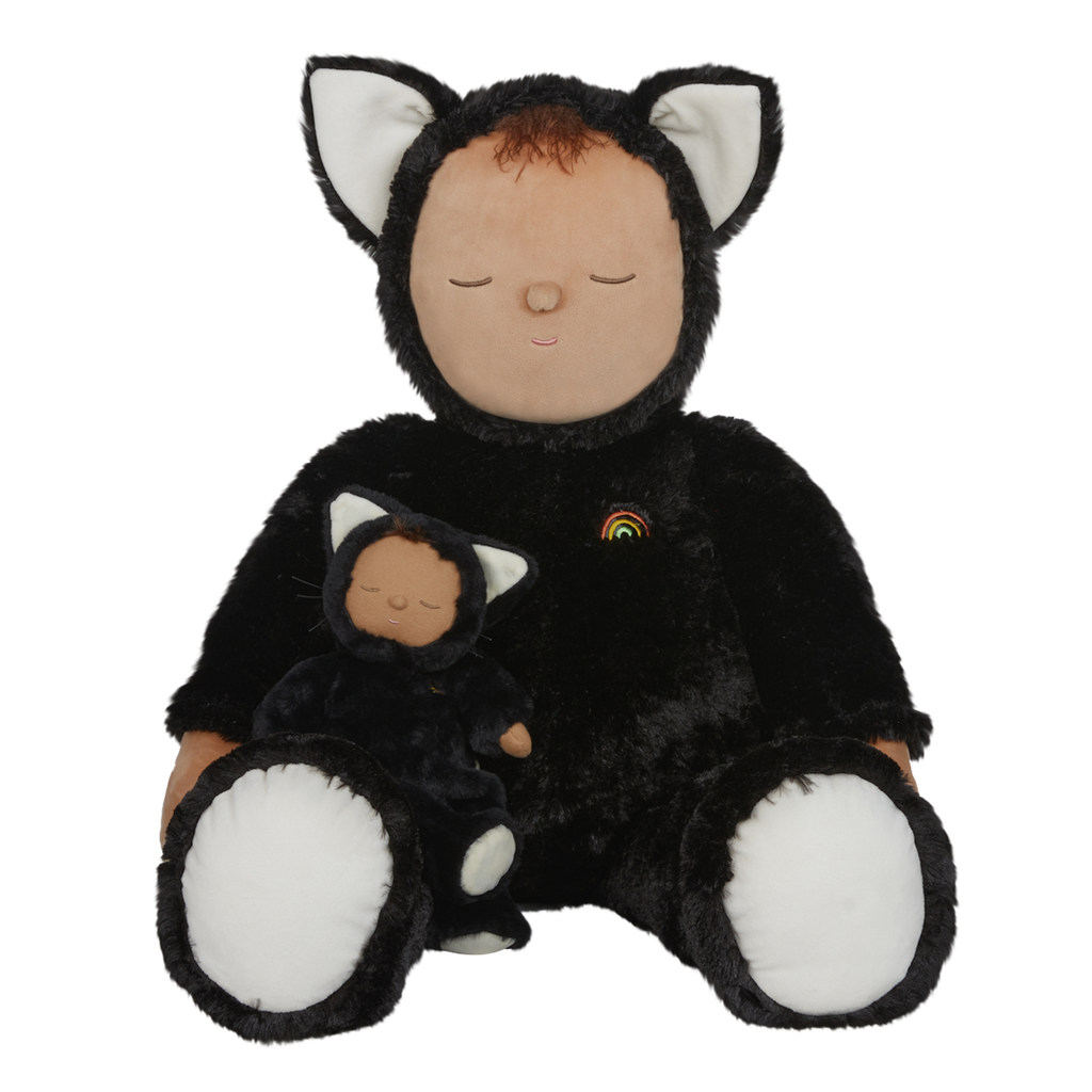 Plush doll dressed as a cat with black fur, white paws and ears, and a tiny rainbow on its chest. The doll's eyes are closed, creating a peaceful expression.