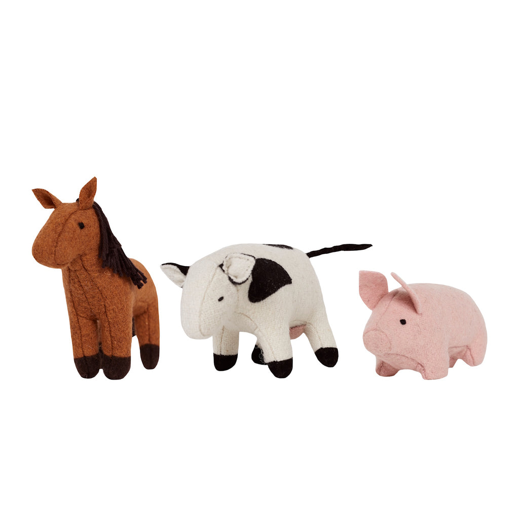 Three felt farm animal toys on a white background: a brown horse with a dark mane, a white cow with black spots, and a pink pig, conveying a playful tone.