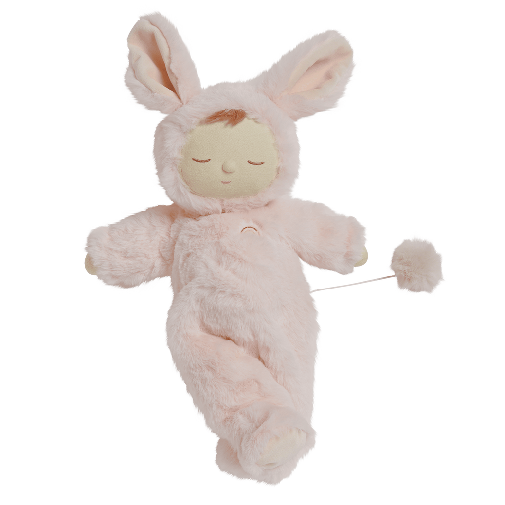 A plush doll in a pink bunny outfit with long ears, closed eyes, and a peaceful expression. It has a tail with a fluffy pom-pom attached.