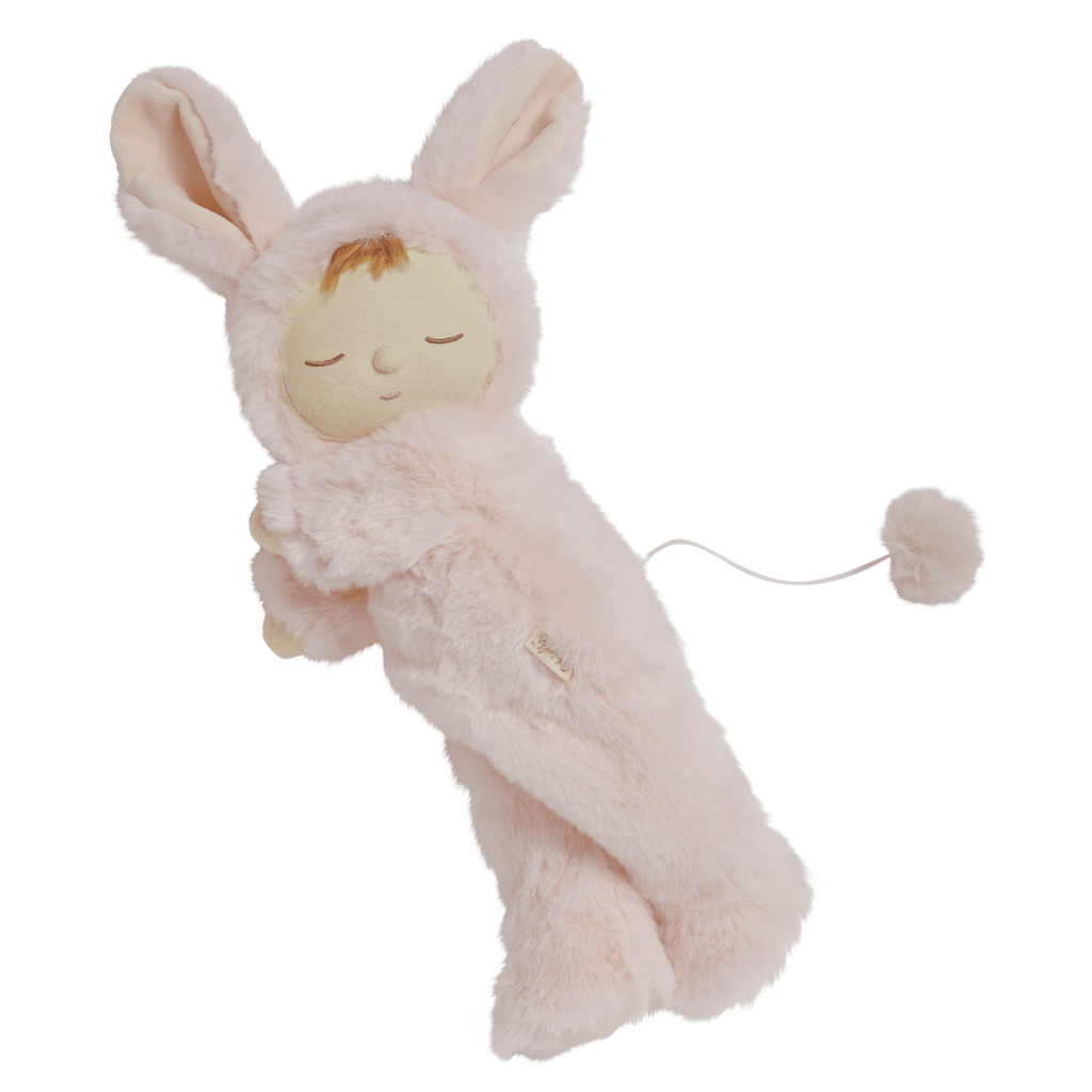 A plush doll in a pink bunny outfit with long ears, closed eyes, and a peaceful expression. It has a tail with a fluffy pom-pom attached.
