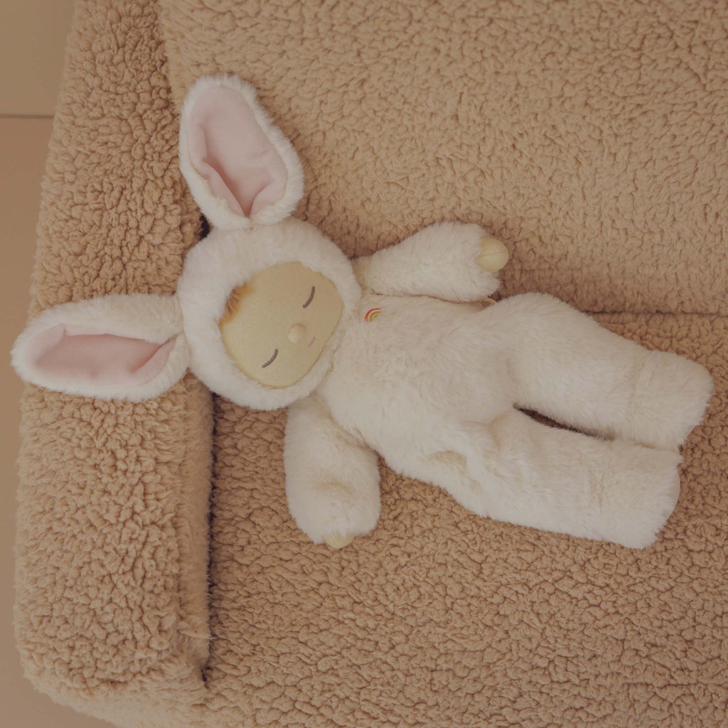 A plush doll in a pink bunny outfit with long ears, closed eyes, and a peaceful expression.