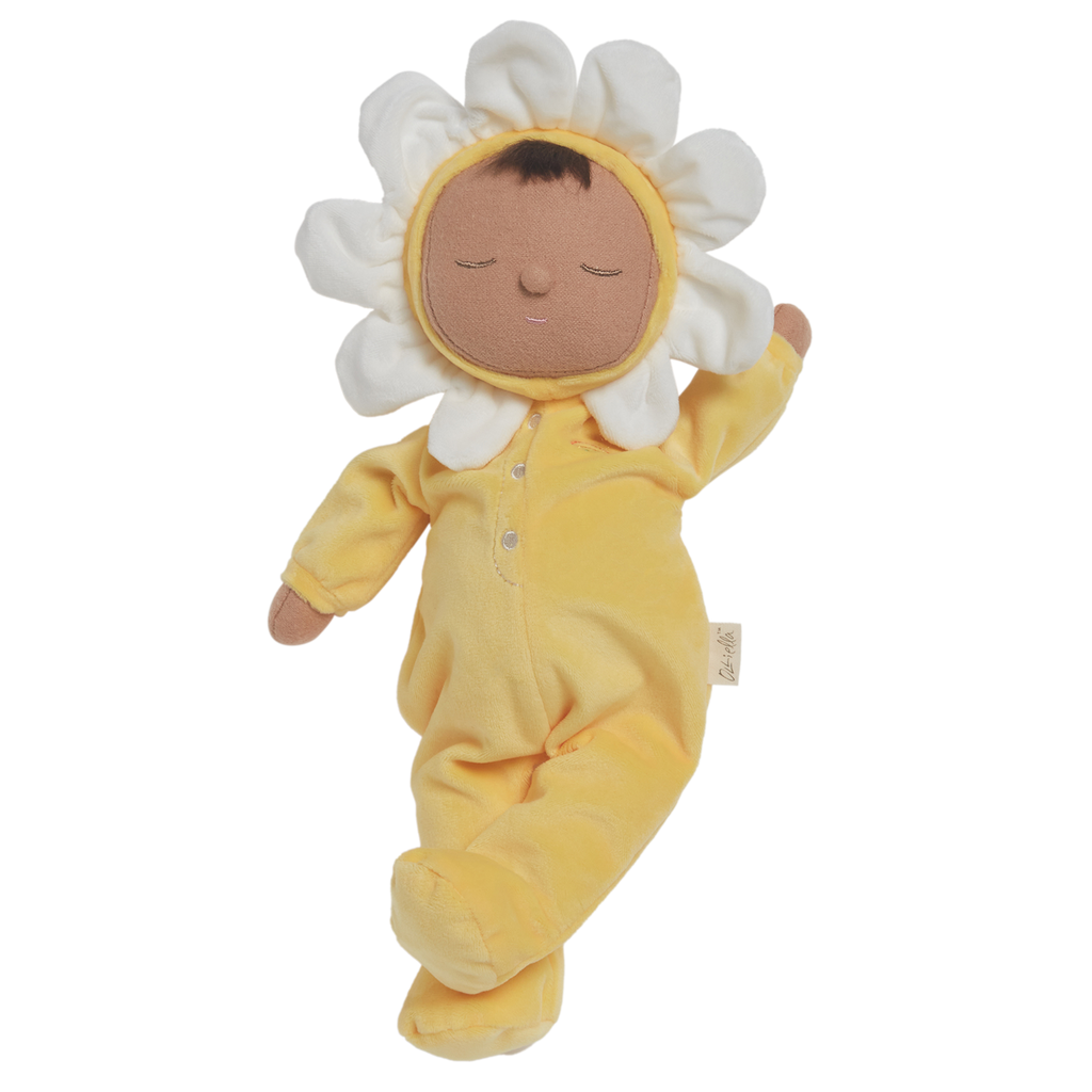 A plush doll with a light brown face framed by white petals, resembling a flower. It wears a soft, yellow bodysuit, conveying a calm, playful vibe.