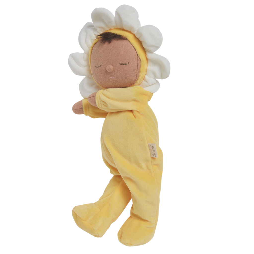 A plush doll with a light brown face framed by white petals, resembling a flower. It wears a soft, yellow bodysuit, conveying a calm, playful vibe.