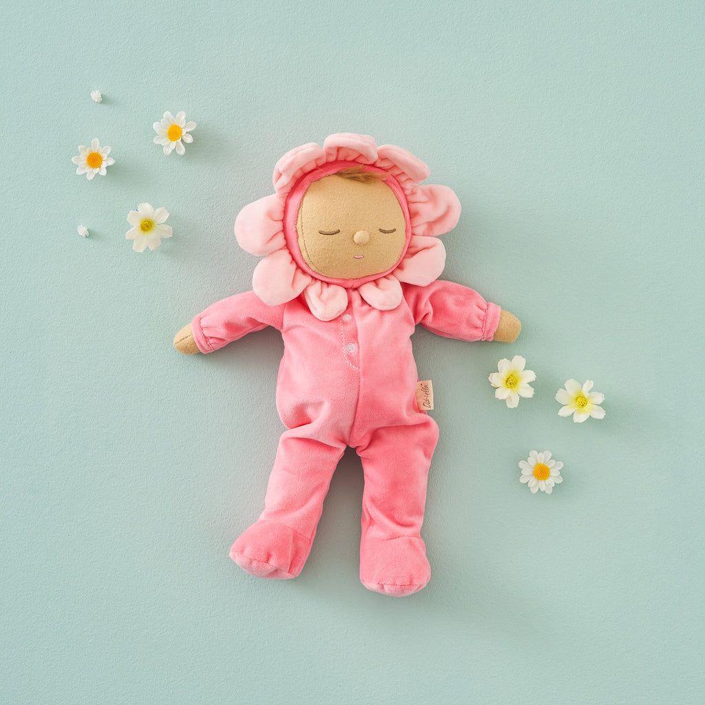 A soft plush toy in a pink floral outfit with closed eyes. The head is encircled by pink petals, evoking a flower. The toy conveys calmness.