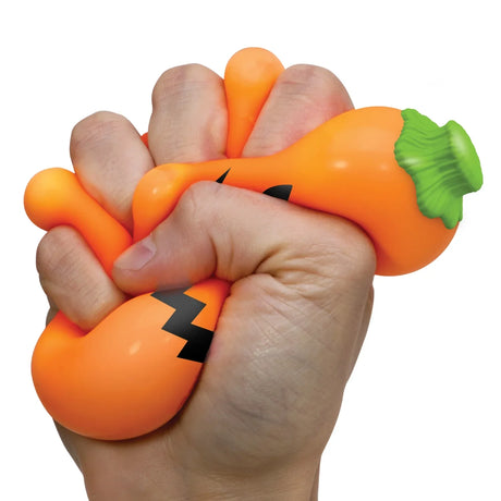 Hand squeezing an orange NeeDoh Jack-Glow Lantern pumpkin stress ball fidget toy with a green stem and jack-o'-lantern face.