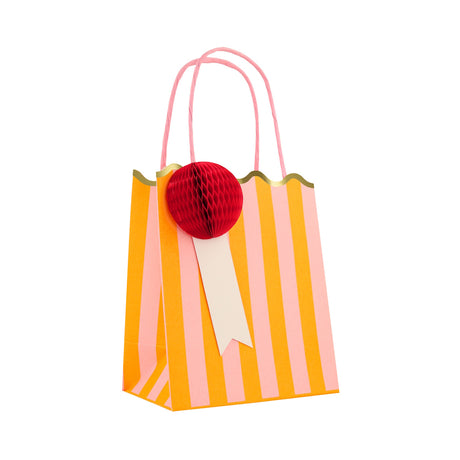 Meri Meri orange and pink striped party bag with a red honeycomb pom-pom and scalloped gold trim.