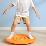 Child standing on an orange sensory balance maze board with marbles in the track.