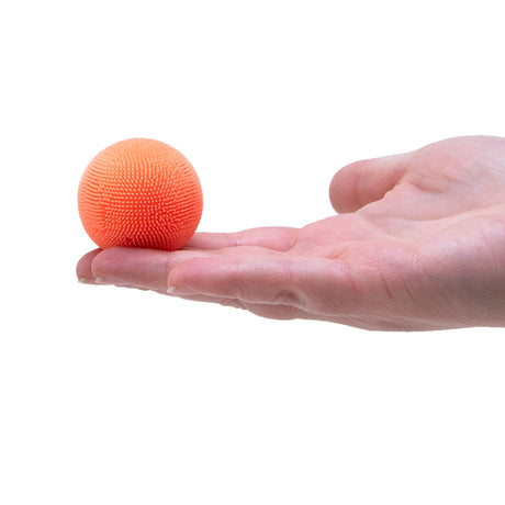 An open hand holding a small, spiky orange fuzzy ball against a plain white background.