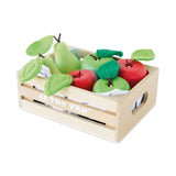 Wooden crate filled with toy apples and pears with felt leaves on a plain background.