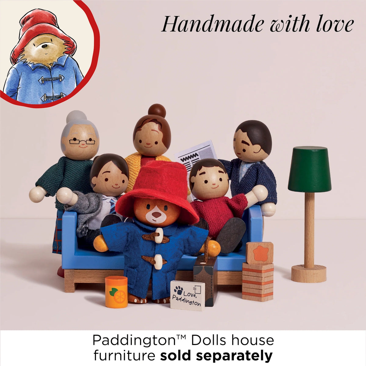 Wooden Paddington Bear standing in front of family dolls gathered around a couch with mini accessories.